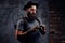 Portrait of a handsome bearded traveler in a hat with a backpack and tattooed arms, holds a photo camera, on a