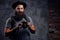 Portrait of a handsome bearded traveler in a hat with a backpack and tattooed arms, holds a photo camera, on a