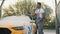 Portrait of handsome bearded young African man washing his yellow car with foam at at self service car wash outdoors