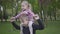 Portrait handsome blond boy playing with her cute sister in the park holding her on his shoulders. The boy trying to
