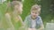 Portrait of a handsome boy and adorable girl with long hair looking into camera of a laptop in the park. Summertime