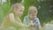 Portrait of a handsome boy and pretty girl with long hair waving hands in the camera of a laptop in the park. Summertime