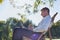 Portrait of handsome businessman drinking coffee and reading newspaper while sitting on folding chair in park