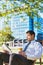 Portrait of handsome businessman drinking coffee and reading newspaper while sitting on folding chair in park