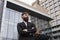 Portrait of an handsome businessman wearing jacket over office building in financial district outdoors. Young bearded