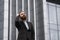 Portrait of an handsome businessman wearing jacket over office building in financial district outdoors. Young bearded