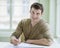 Portrait of handsome businessman writing on document at desk in office