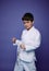 Portrait of a handsome Caucasian teenage boy, aikido wrestler practicing martial skills against purple wall background. Oriental