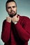 Portrait of handsome fashion stylish hipster lumbersexual model dressed in warm red sweater posing in studio