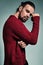 Portrait of handsome fashion stylish hipster lumbersexual model dressed in warm red sweater posing in studio
