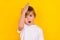 Portrait of handsome funny lost puzzled pre-teen boy touching forehead oops forgot  over bright yellow color