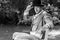 Portrait of handsome gentleman dressed in vintage costume, holding hat, sitting on garden bench