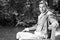 Portrait of handsome gentleman dressed in vintage costume sitting on bench in garden