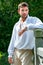 Portrait of handsome gentleman dressed in vintage costume standing on bridge of stately home with trees in background