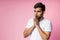 Portrait of handsome Indian guy standing on pink background