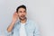 Portrait of handsome interested male placing hand on ear asking someone to speak up, isolated over white background. Young stylish