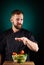 Portrait of a handsome male chef cook making tasty salad on a blurred aquamarine background