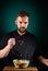 Portrait of a handsome male chef cook making tasty salad on a blurred aquamarine background