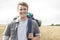 Portrait of handsome male hiker with backpack standing on field