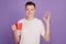 Portrait of handsome man hold cellphone coffee cup show okey gesture on purple background