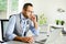 Portrait of handsome man male doctor in medical practice office writing prescription in laptop computer