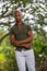 Portrait of a handsome man posing arms crossed and blurry trees in the background at a park setting