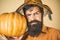 Portrait of Handsome man with pumpkin over  background. Devil man. Young man with witch hat ready to Halloween