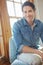 Portrait of a handsome man smiling and sitting in a sunroom. Happy attractive male chilling at home. Handsome guy