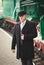 portrait of handsome man in suit and bowler hat waiting for train