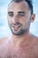 Portrait of handsome man with white teeth smile, blue eyes, wet body, surfer and blue ocean