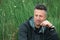 Portrait of handsome mid-adult man posing on summer meadow with blade of grass