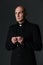 Portrait of handsome priest standing and holding rosary