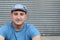 Portrait of handsome real looking man in hat sitting outdoors