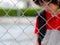 Portrait of handsome sad boy behind fence mesh netting.