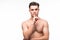 Portrait of handsome shirtless man showing silent gesture, white background