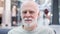 Portrait of handsome smiling senior man sitting in shopping mall. Retired male shopper waiting