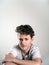 Portrait of handsome teenager boy with curly hair on gray background. Adolescent, teenager.