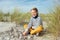 Portrait of handsome teenager boy sitting on white sand on beach of Baltic sea