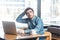 Portrait of handsome thoughful bearded young businessman in blue jeans shirt are sitting in cafe and typing message on laptop,