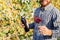 Portrait of handsome wine maker holding in his hand bottle and a glass of red wine and tasting it, checking wine quality while