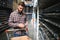 Portrait of a handsome workman choosing water pipes and pipe joints standing near the showcase in the plumbing shop