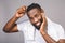 Portrait of handsome young african american black man combing his hair in bathroom. Isolated over grey background