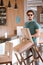 Portrait of handsome young bearded male lifting the chair at cafe.