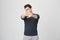 Portrait of handsome young caucasian guy with stylish haircut stretching hands at camera showing stop or enough gesture