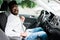 Portrait of handsome young indian man sitting in driving seat of car and wearing seatbelt for safety