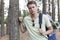 Portrait of handsome young man with backpack hiking in forest