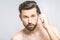 Portrait of handsome young man combing his hair in bathroom. Isolated over grey background