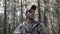 Portrait of handsome young man hunter or tourist. Man in camouflage clothes hunts outdoor in forest hunting alone. Close