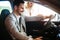 Portrait of handsome young man taking luxury car for test drive, sitting inside and smiling