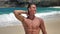 Portrait of handsome young man, the well-trained muscular athlete, posing on beautiful beach